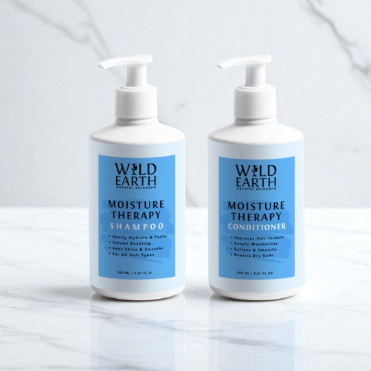 Two bottles of Wild Earth Moisture Therapy Shampoo and Conditioner on a white surface with a light gray background.