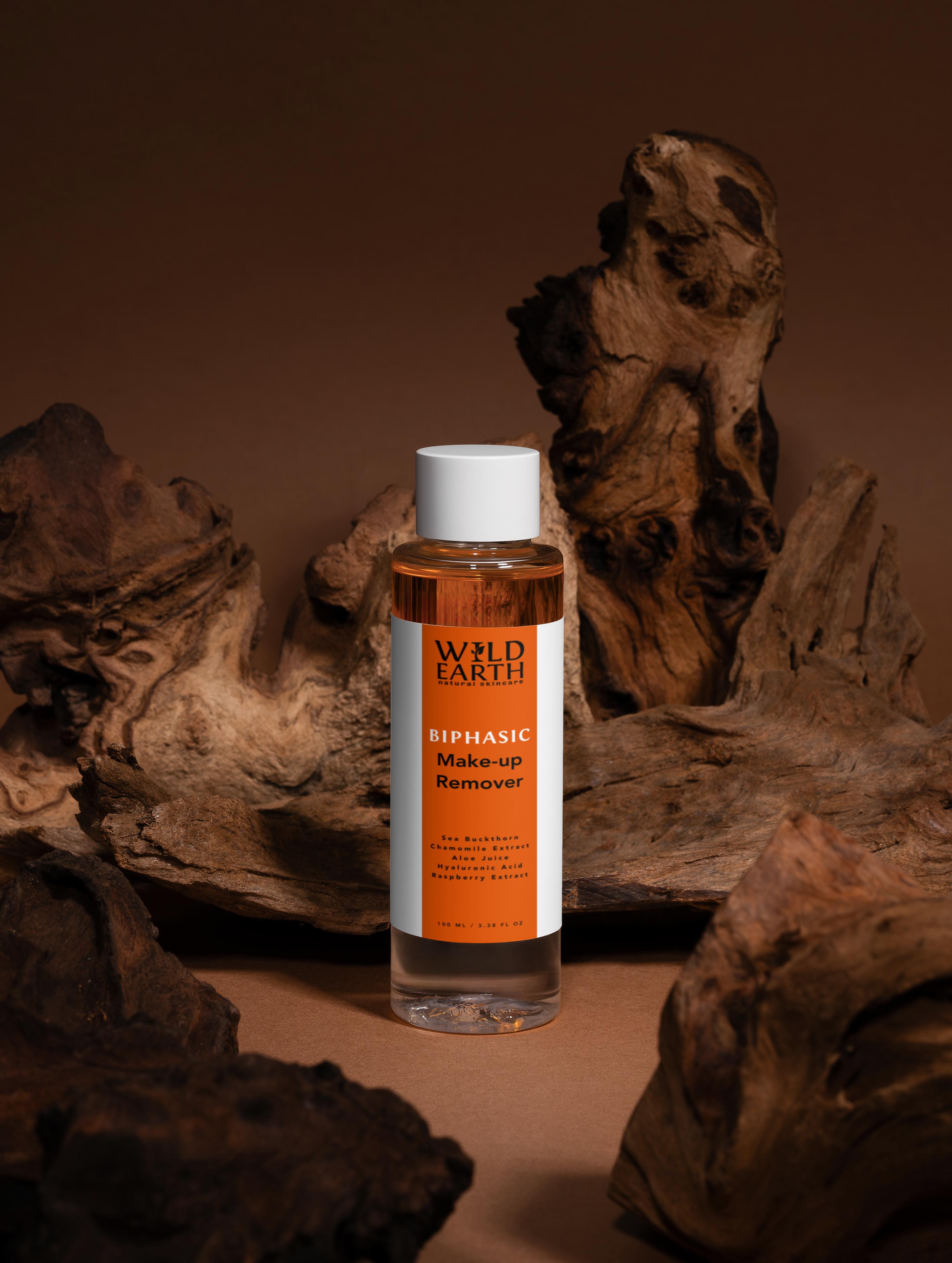 Bottle of Wild Earth BiPhasic Make-up Remover on a brown background with natural elements.